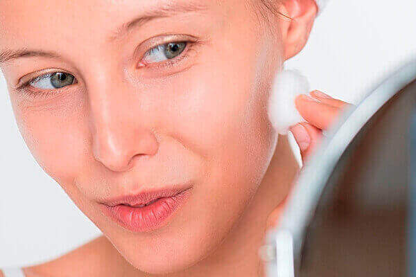 Woman applying toner on face