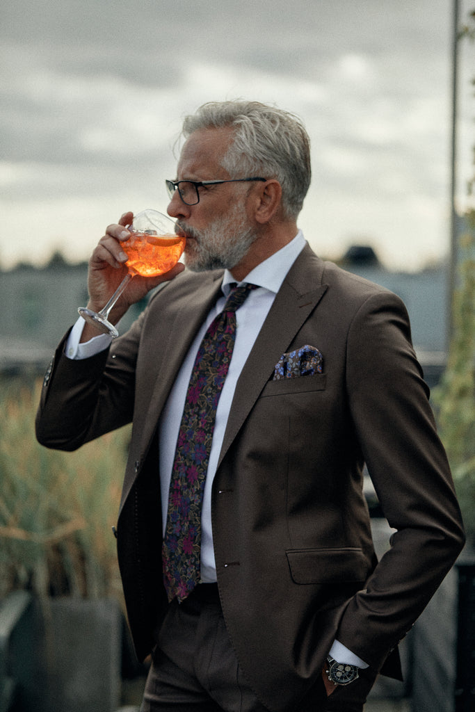 mand iført jakkesæt drikker cocktail