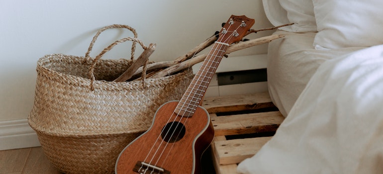 A woven basket and a guitar next to the bed.