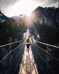 Man on bridge walking towards mountains