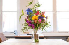 Colourful flowers in a jar on a desk