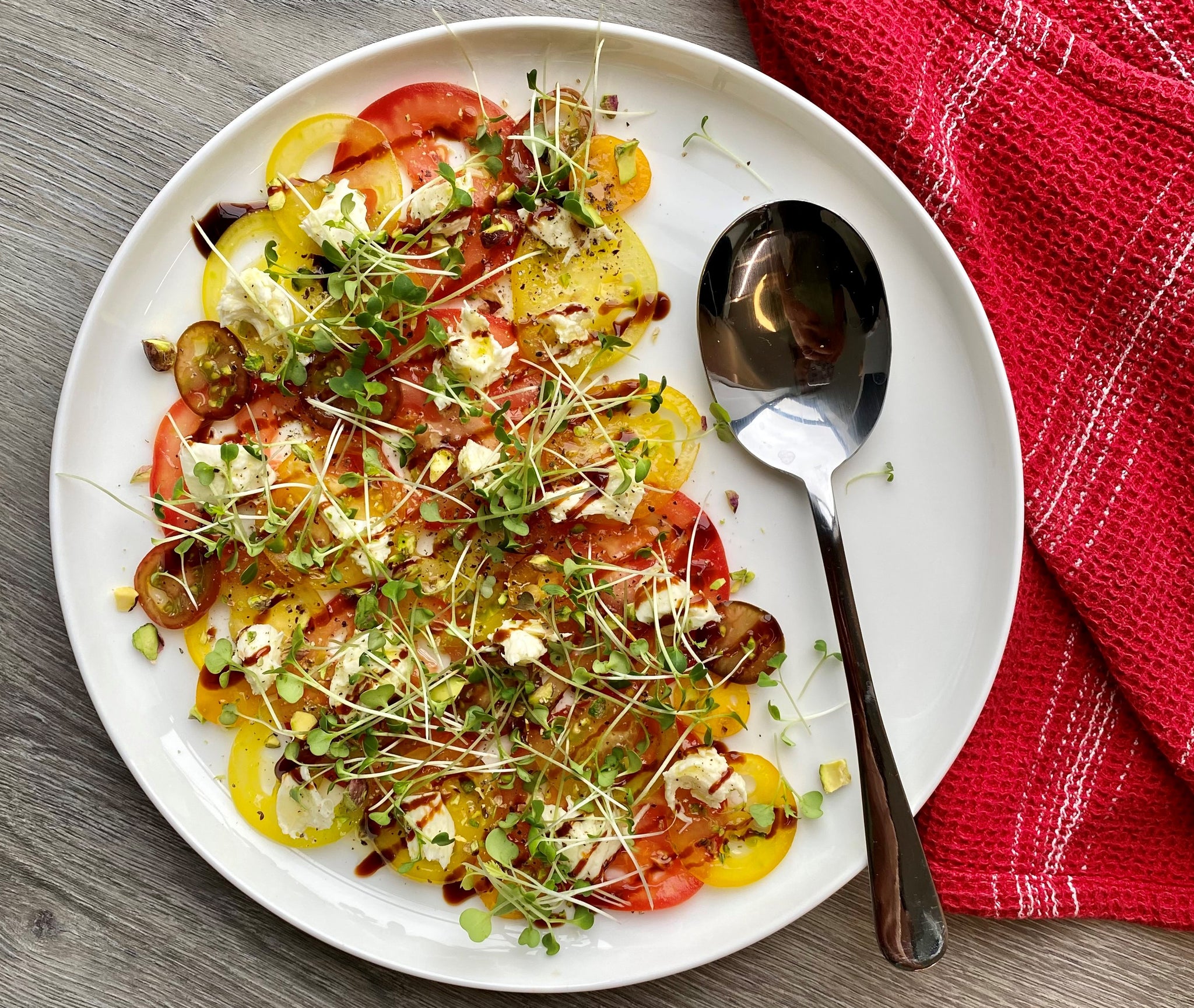 Tomato carpaccio arranged on plate with microgreens