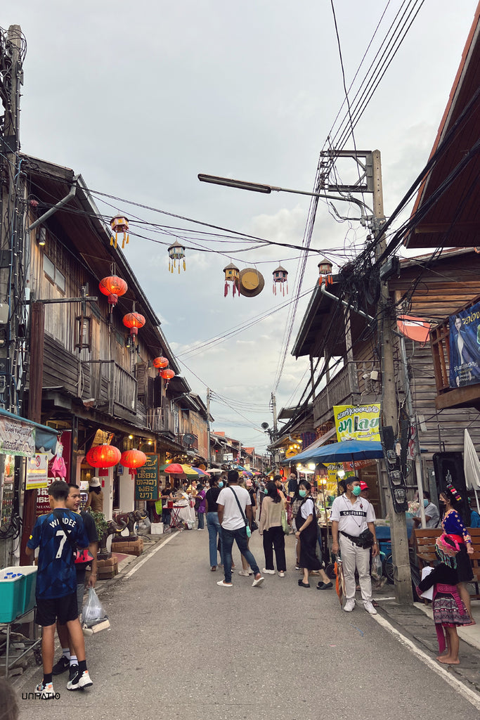 Chiang Khan Night Market bustling with locals and tourists amidst traditional wooden houses and vibrant lanterns, capturing the essence of northeastern Thailand's cultural charm.