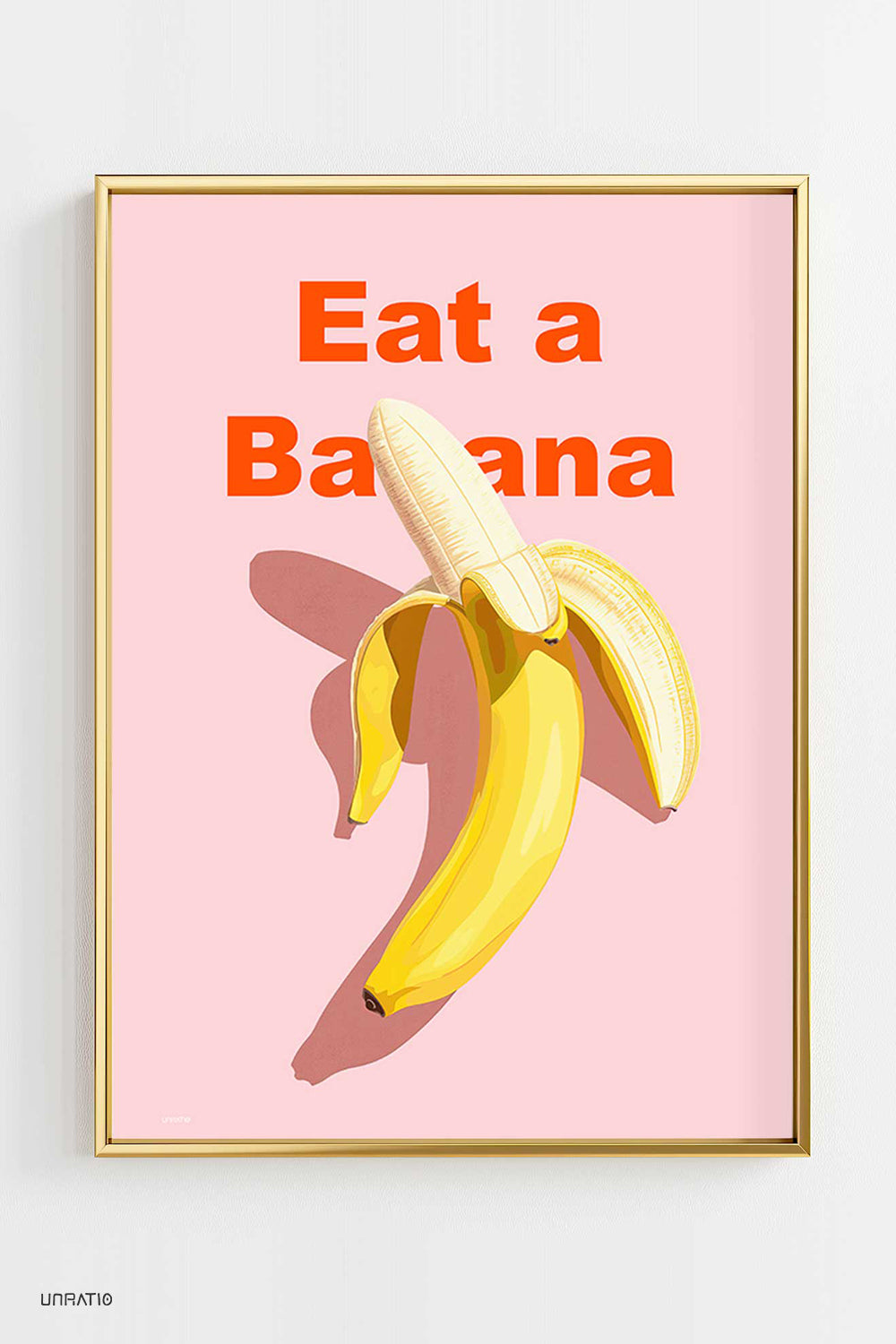 Framed artwork on a wall with a bold 'Eat a Banana' phrase and a vibrant illustration of a banana, invoking healthy living and modern design.