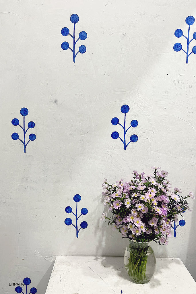 Artistic depiction of blue flowers on a white wall above a vase of daisies, resonating with Dalat's artistic flair and the natural artistry of its floral abundance.