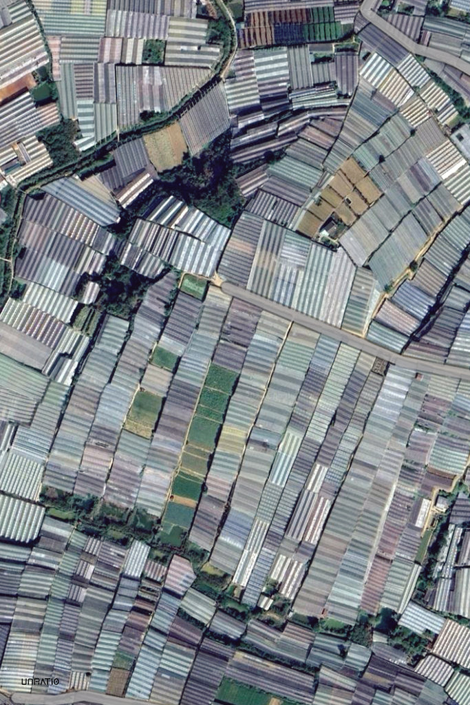 A patchwork of industrial-scale greenhouses in Dalat's countryside, as seen from above, showcasing the city's extensive agricultural prowess and greenhouse farms.