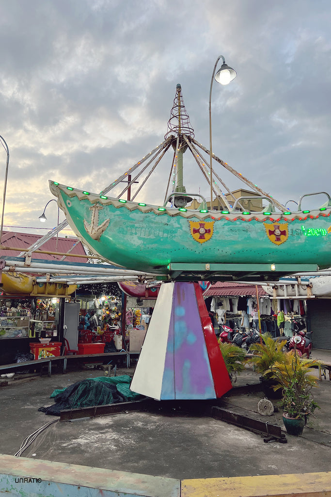Kampot market's enchanting carousel with a boat ride glowing under the evening sky, offering a glimpse into the vibrant street life and culture.