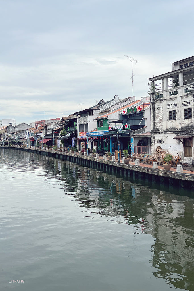 Historic shop houses along the Melaka canal, with Peranakan architecture and a cafe by the water.