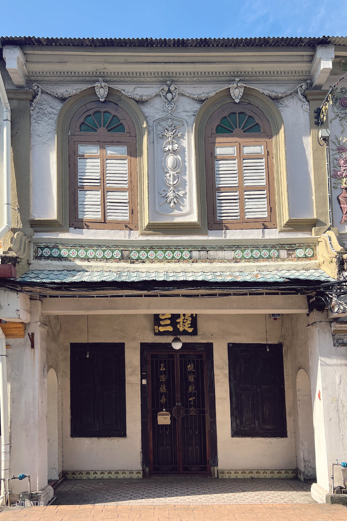 Traditional Peranakan-style facade of an old house in Melaka with ornate decorations and wooden shutters.