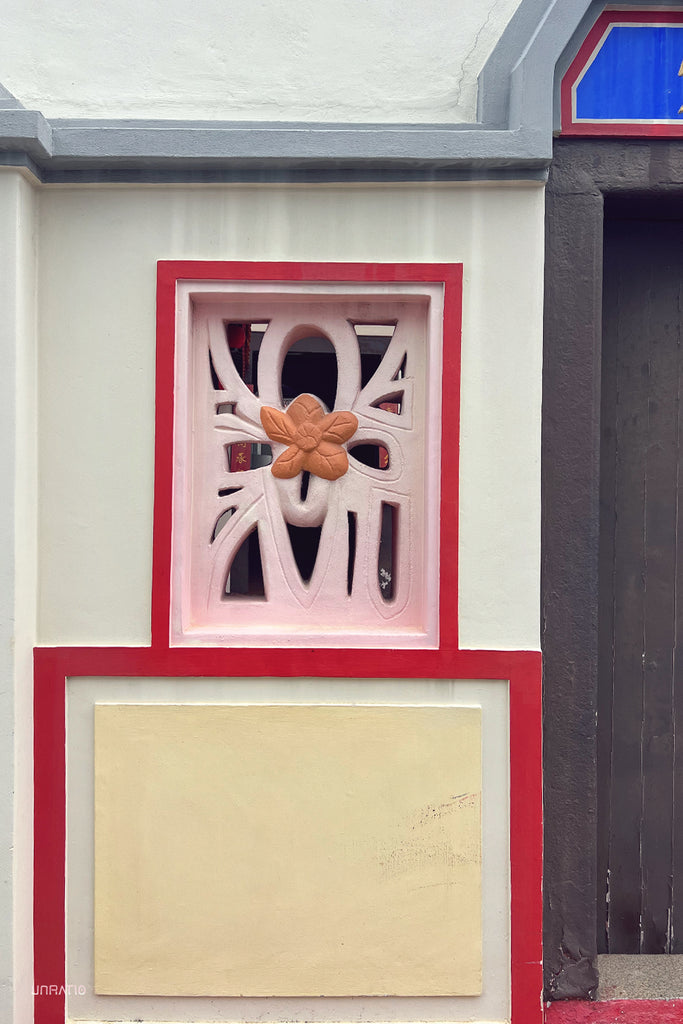 Detailed Chinese wall carving with floral motifs, contrasting with bold geometric patterns in Melaka.