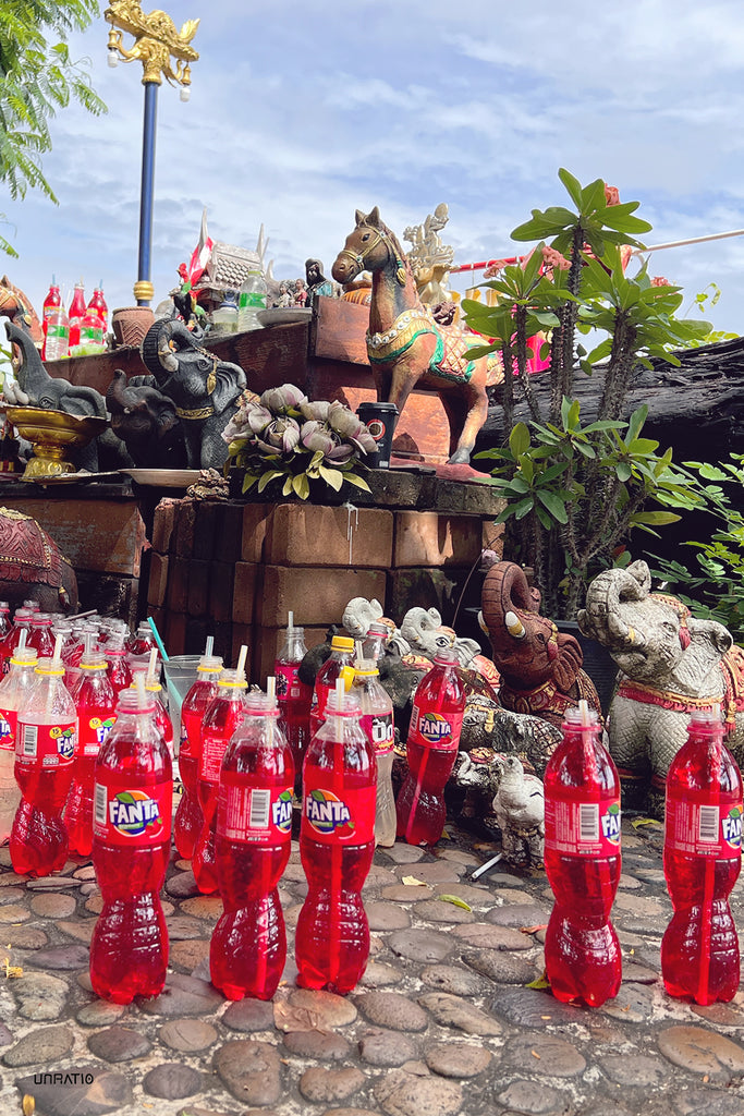 Traditional Thai shrine adorned with offerings of red Fanta bottles, surrounded by elephant statues and lush foliage, showcasing local spiritual customs in Chiang Khan.