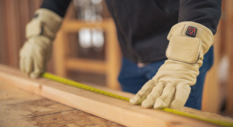 Man wearing Gobi Heat Drift work gloves measuring a piece of wood with measuring tape