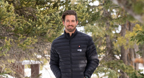 Man in the snow surrounded by trees wearing a black Gobi Heat Wolf jacket