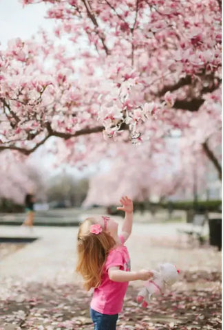 little girl under cherry blossom tree