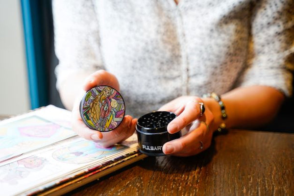 close up of Courtney Hannen holding a cannabis grinder with her artwork on it