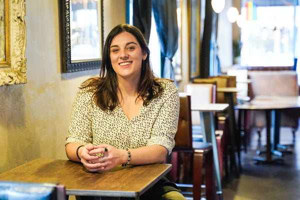 The artist Courtney Hannen sitting at a cafe table, smiling at the camera