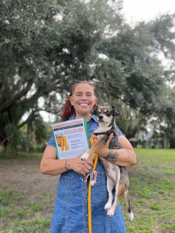 Woman and her newly adopted dog stand outside hugging and holding Mighty Paw Yak Chew.