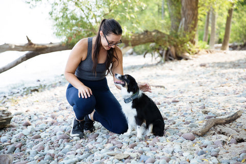 Woman outside petting her black and white dog.