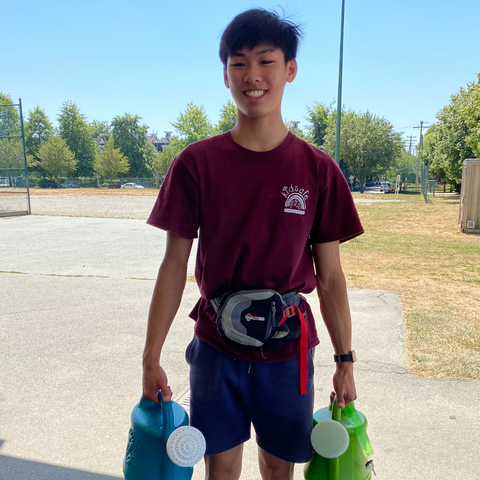 Volunteer at KidSafe standing holding watering cans