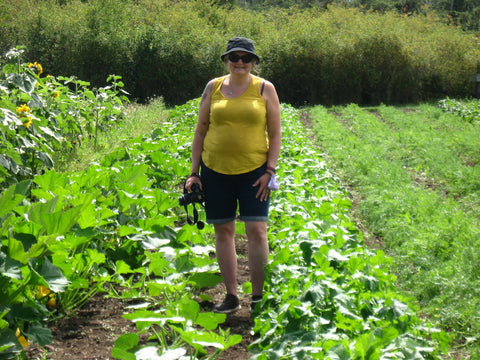 Person standing in garden with camera at the Farmland Trust Society (Greater Victoria)