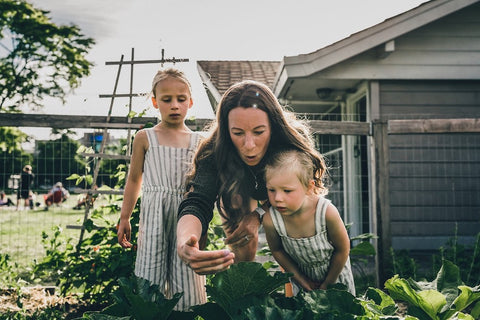 Young family gardening together, looking at a plant. Sight is a mindful gardening technique.