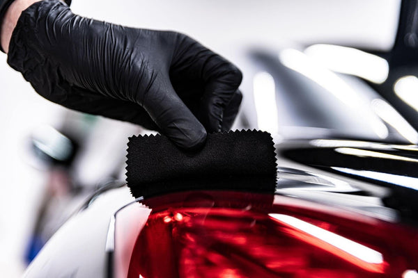 Employee of a car wash or a car detailing studio applies a ceramic coating to the paintwork