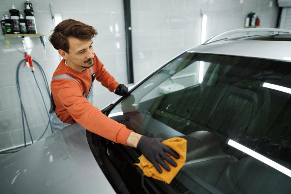 Professional car detailer wiping car windshield with microfiber towel in his garage carcarez blog image