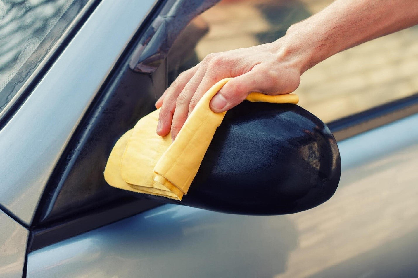 waterless car wash. Men's hand with yellow cloth cleaning car photo with toning carcarez