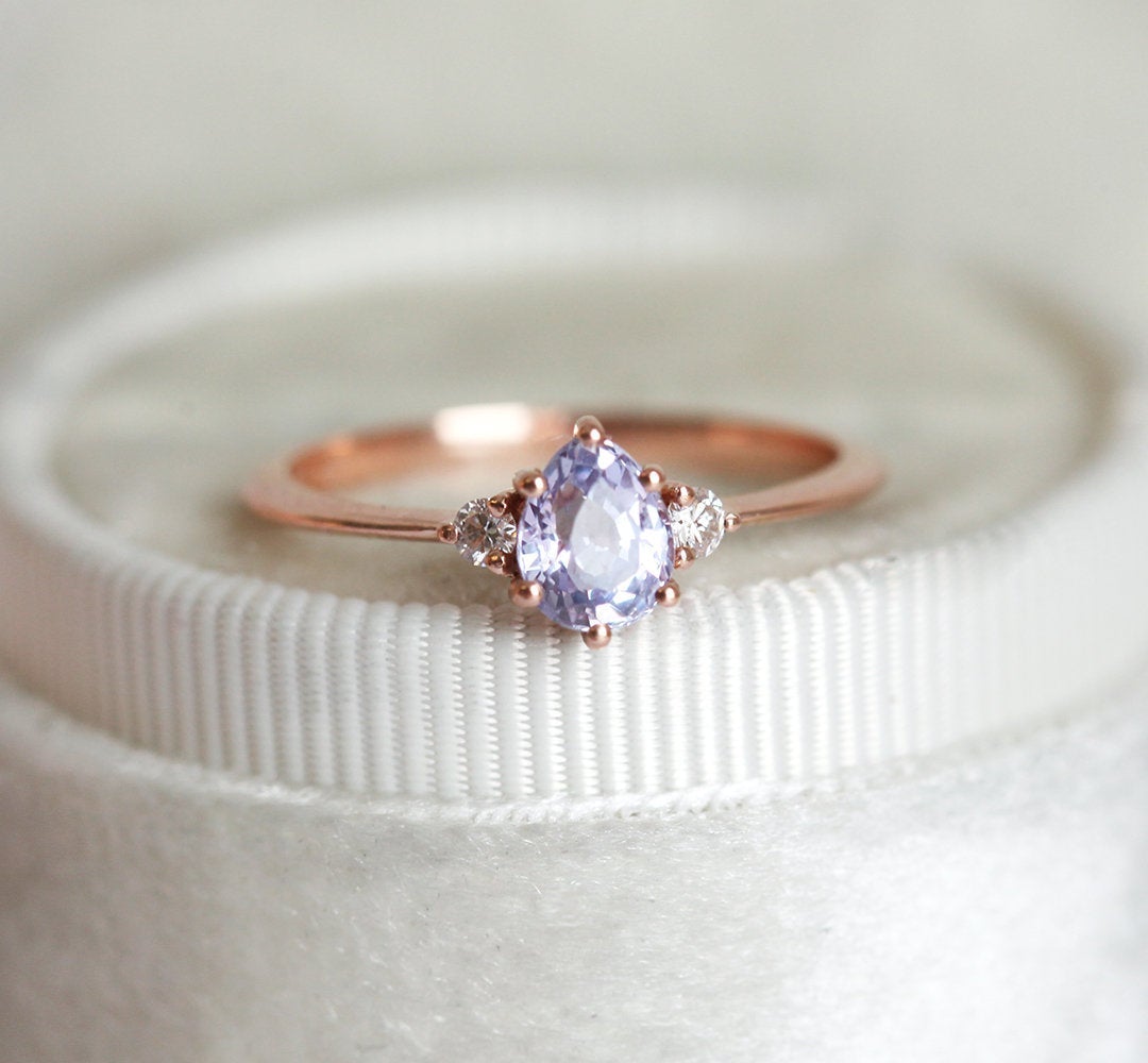 Un anillo de zafiro color lavanda con detalles de diamantes y una banda de oro