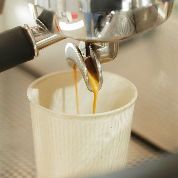 Espresso coffee being extracted into a coffee cup