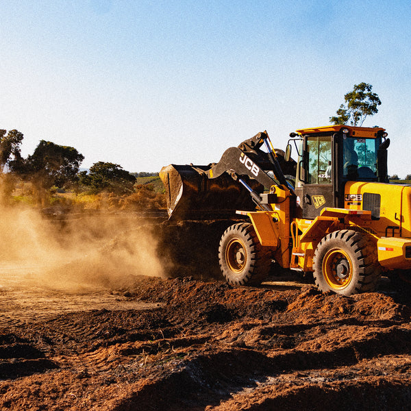 Image of JCB tractor sewing the land for coffee farming