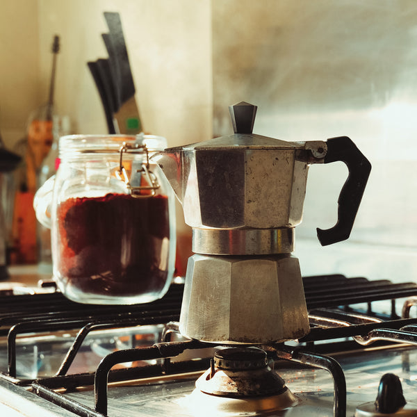 Moka Pot on top of hob brewing coffee in a kitchen 