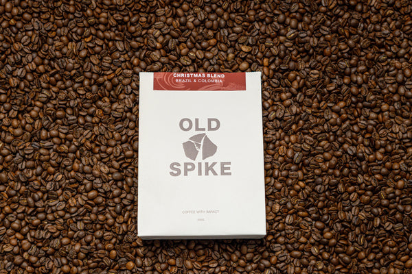 Bag Old Spike Christmas Blend laying on top of coffee beans