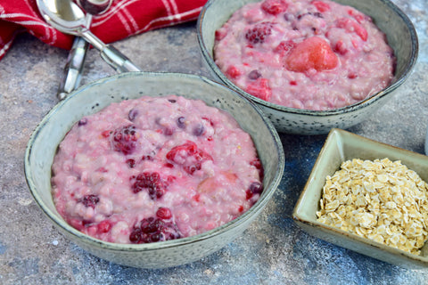 Mixed berry oat porridge for breakfast with maple syrup stock photo