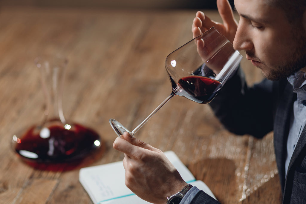 The Sommelier Holds The Glass by The Base and Sniffs The Wine