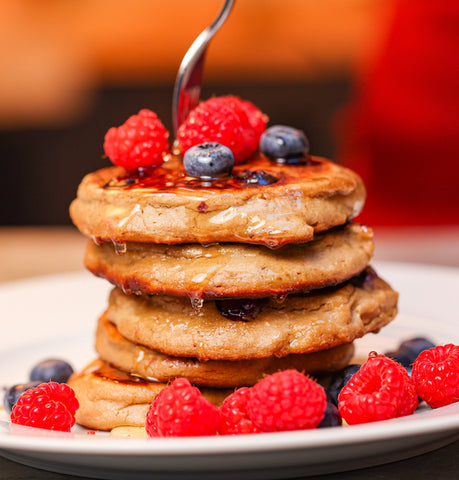 Stack of pancakes with raspberries on top and around