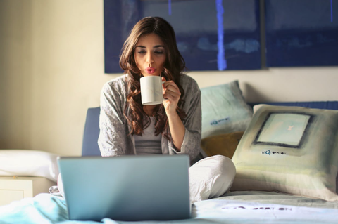girl with a cup in her hand working on her laptop