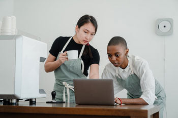 Two professional women look at a laptop computer