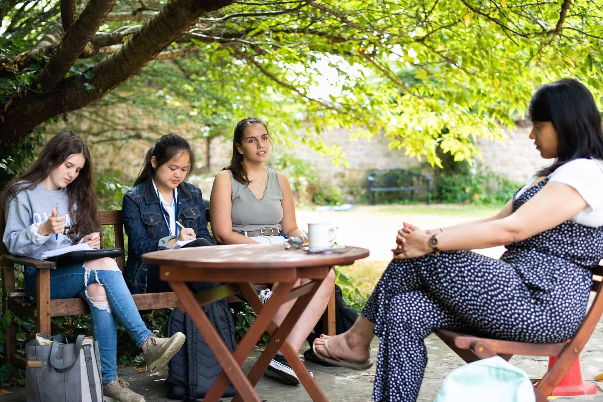 Students sat under a tree in Oxford, the tutor is leading an admissions work shop