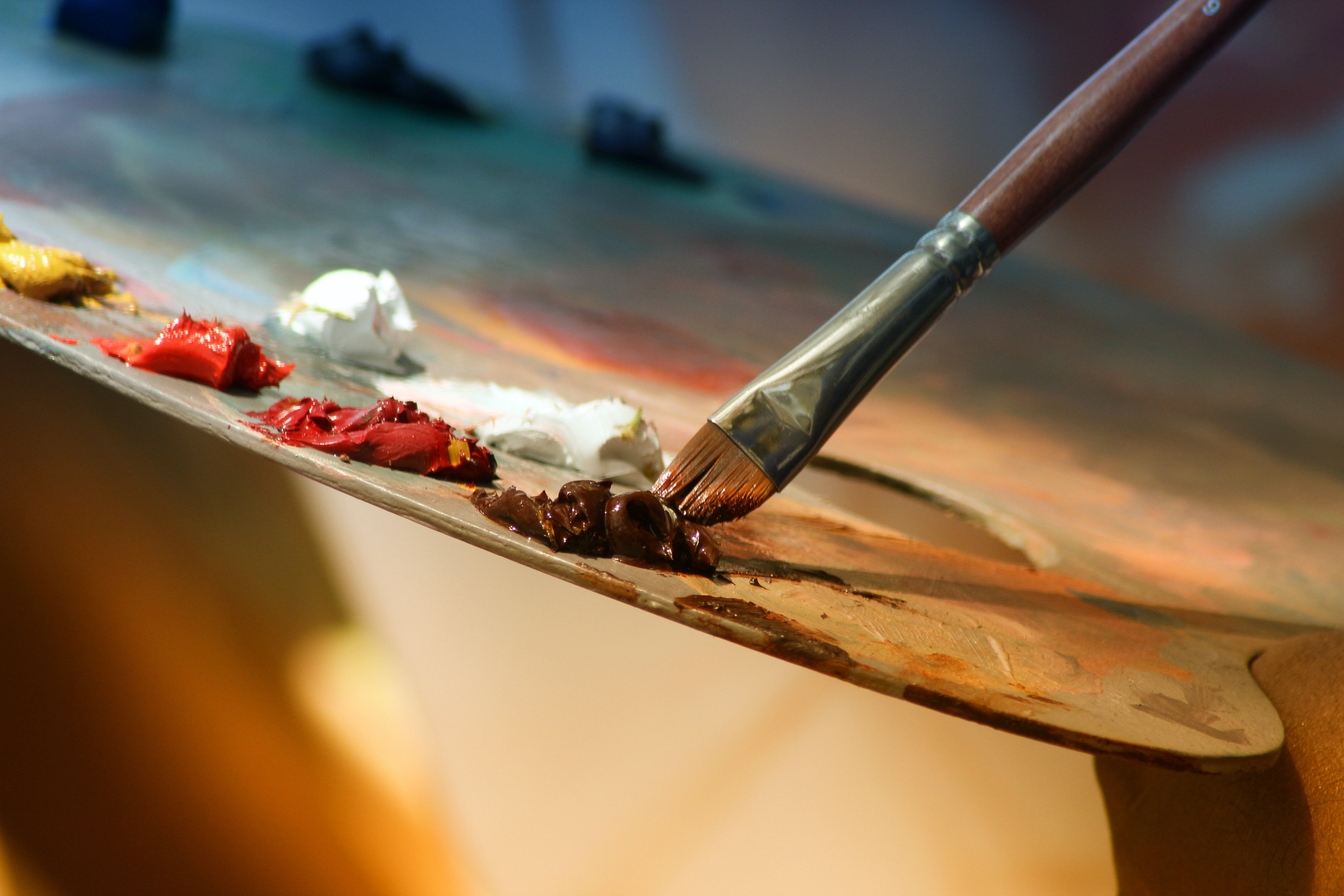 An artist dips their paintbrush into paint on the easel.