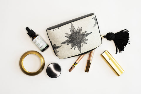 Smell Proof Pouch with star compass print surrounded by a vaporizer, CBD tincture, and other cannabis accessories 