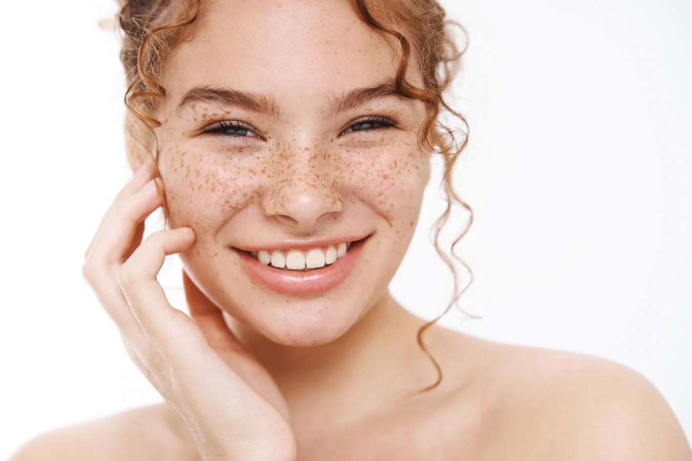 a girl smiling with freckles skincare tips sun exposure vitamin c serum skin's radiance enough sleep glowing complexion