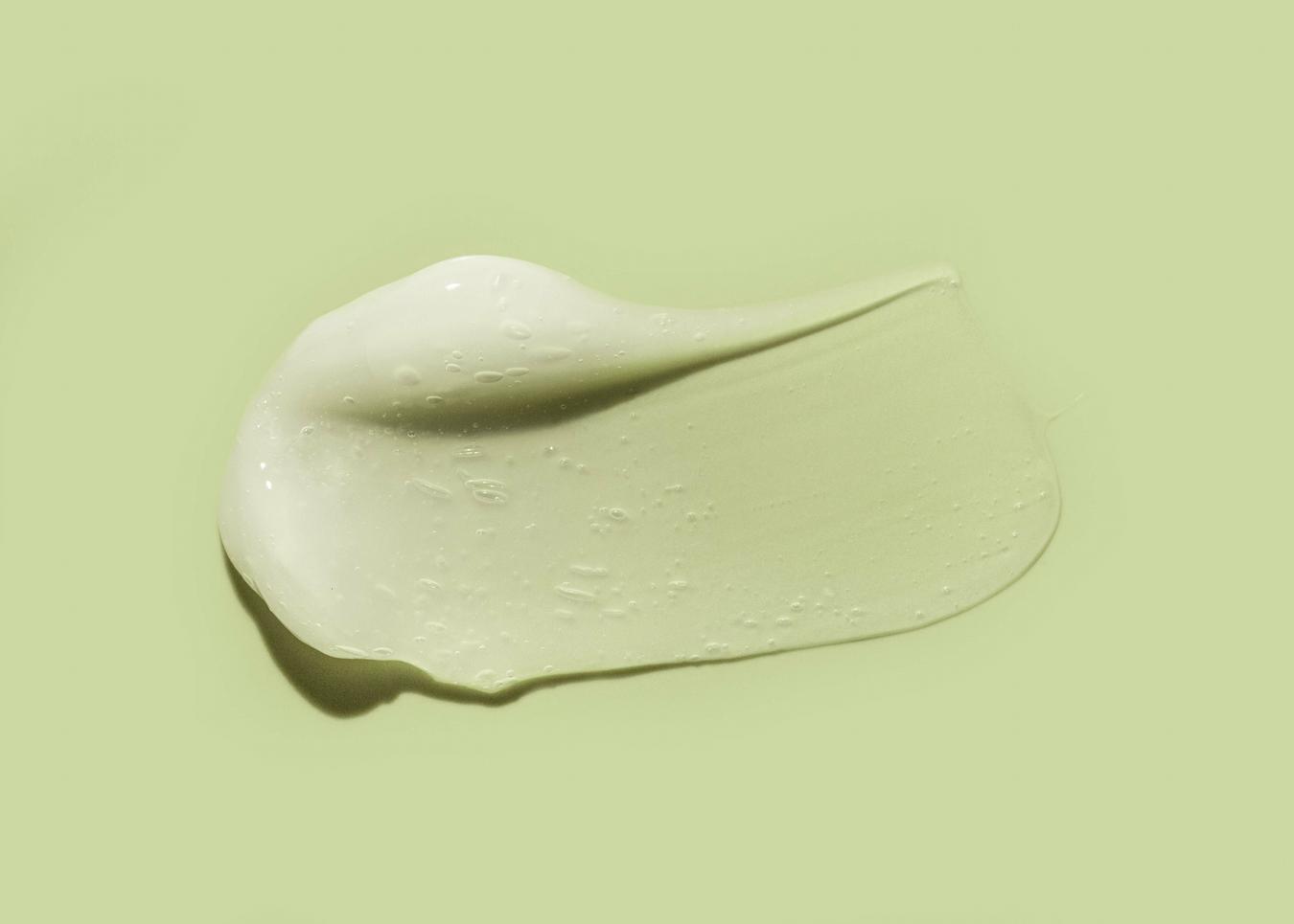 a smear of a facial skincare product on a green background dry skin apply moisturizer dry skin