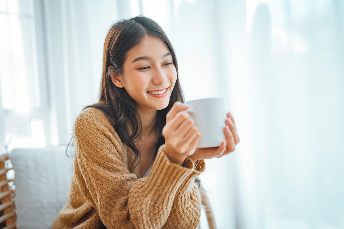 an asian woman smiling while holding a mug of tea high quality tea leaves tea bags silver needle normal cells silver needle tea leaves silver needle tea antioxidant properties