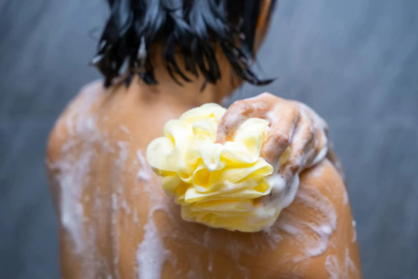 girl using a loofah to wash her shoulders gentle coconut oil surfactants organic body wash brands shea butter