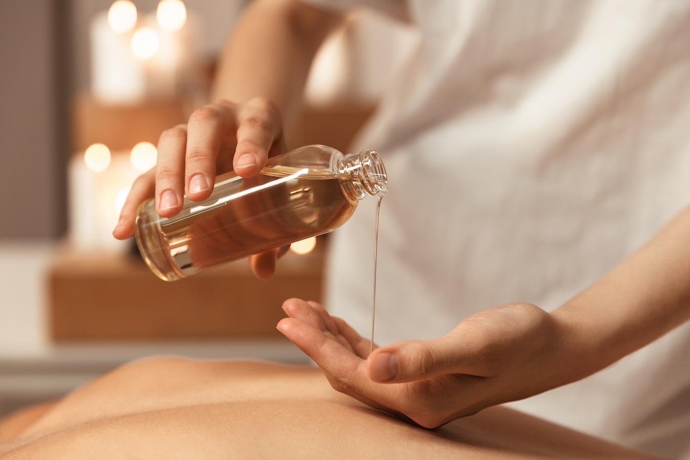 masseuse pouring oil into her hands adds essential oils massage lotion massage therapists skin tone stress relief sweet almond oil carrier oil adding essential oils essential oil carrier oil relaxation essential oil essential oil