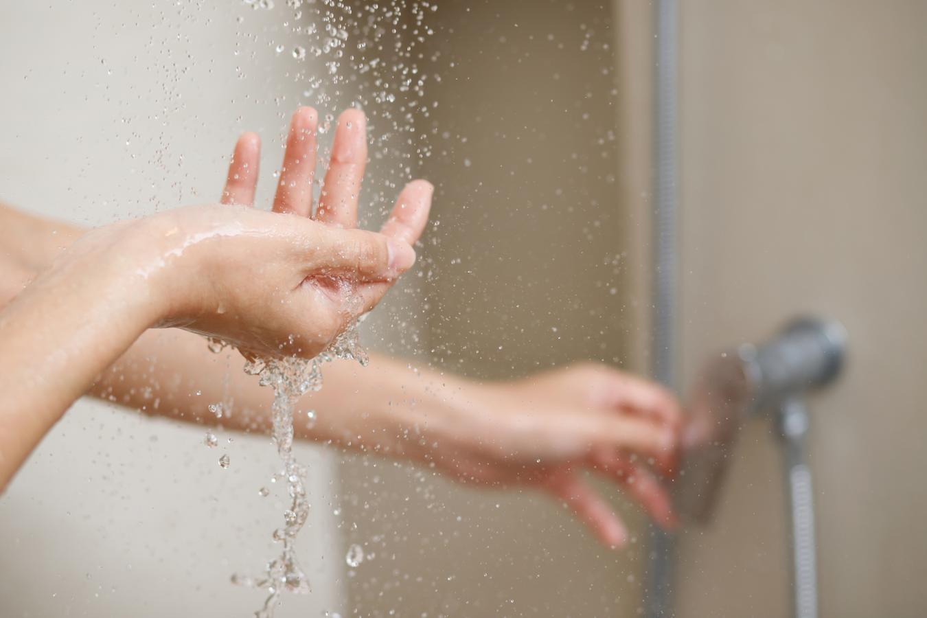 someone cupping water in their hand from the shower synthetic fragrances vitamin e shower gel vs moisturising properties skin care cleansing agents excess oil normal skin shower gel and body wash