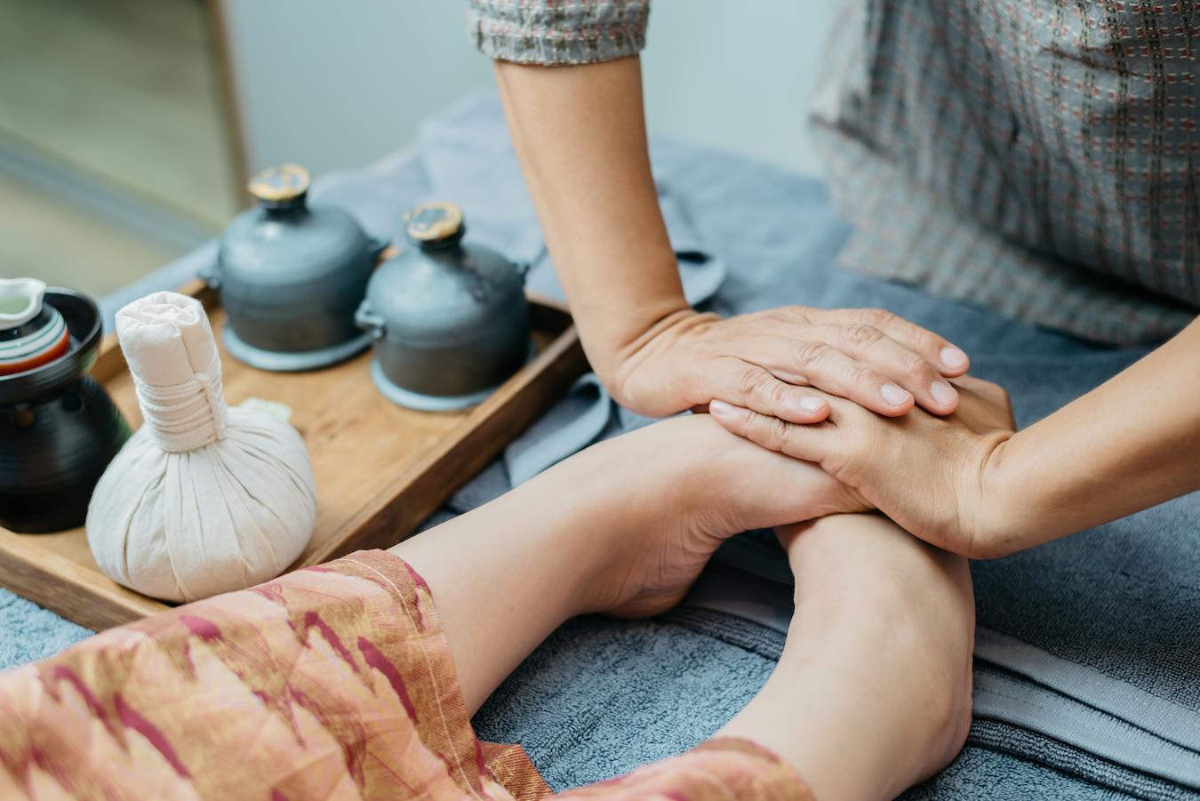 someone massaging feet traditional thai medicine receiving thai massage starts thai massage may reduce tension