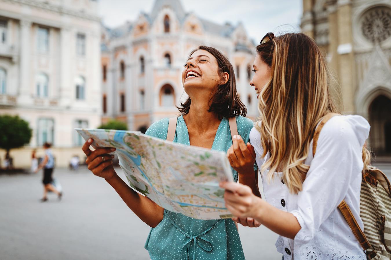 two girls laughing while holding a map supportive friends optimal level other members conscious actions providing support support