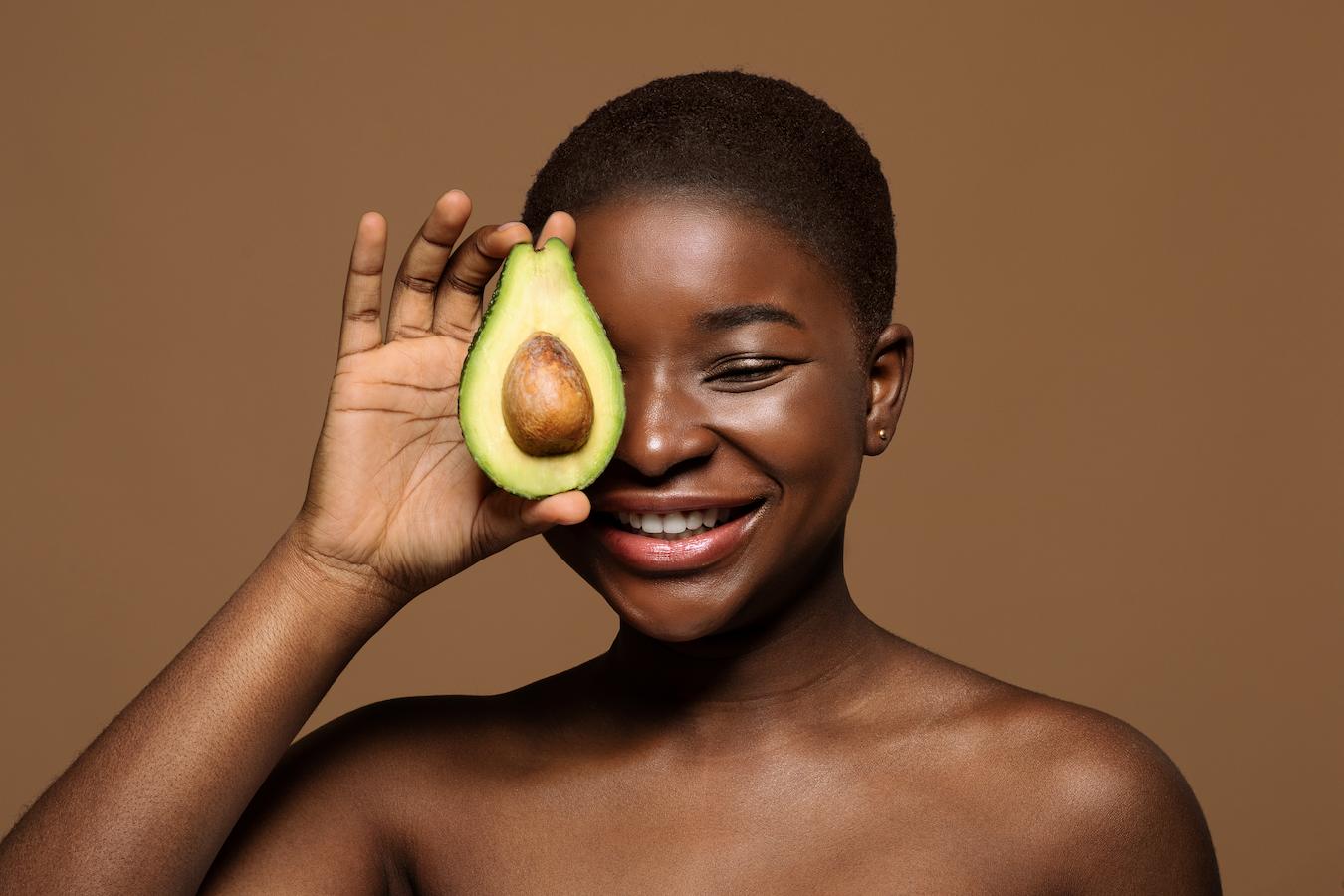 woman holding an avocado half to her face irritated skin dry skin dryness dry skin hydration natural moisturizing factor too much moisturizer